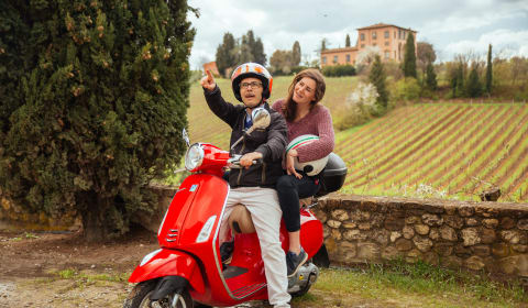 A local guide with a tourist on a red Vespa on a private country side tour in Tuscany from Florence