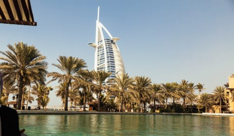 A view from the water to palm trees with the Jumeirah Beach Hotel behind the trees