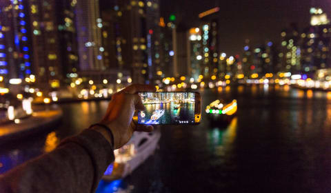A view on a phone taking a night picture of two boats in the water in Dubai