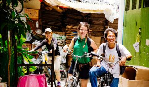 A tourist with a local guide cycling in Bangkok of the main roads