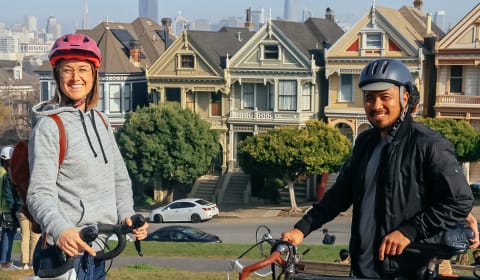 A local guide and tourist on bikes posing in front of the Painted Ladies in San Francisco