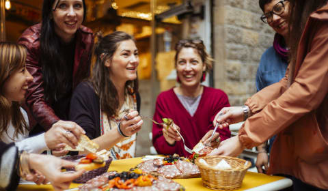 A group of tourist sharing food on a table a t home dinner with a local host in Florence