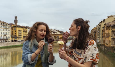 Two tourists having an Italian Gelato or ice cream in Florence at the river