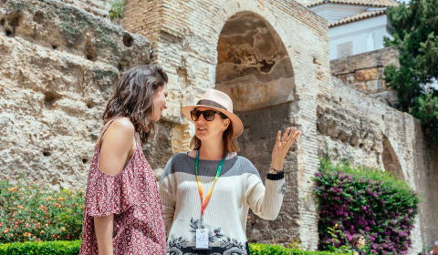 A local guide showing a tourist some ancient walls in Malaga
