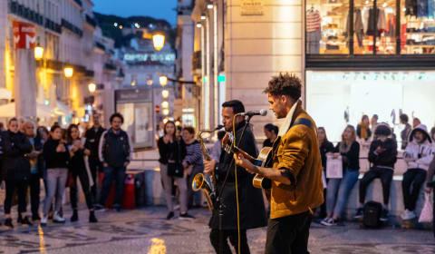 Two musicians with a saxophone and guitar on the streets in the evening of Lisbon