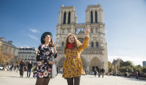 Two tourists standing in front of the Notre Dame in Paris