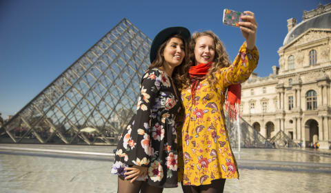 Two tourists taking a selfie at the Louvre in Paris