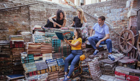 A group of tourists posing the book steps at Libreria Acqua Alta in Venice