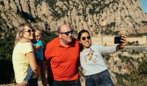 A family and a local guide taking a selfie on a Montserrat day trip from Barcelona