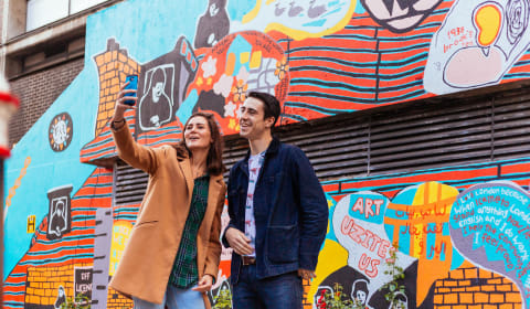 Two tourist taking a selfie at a graffiti murial in London