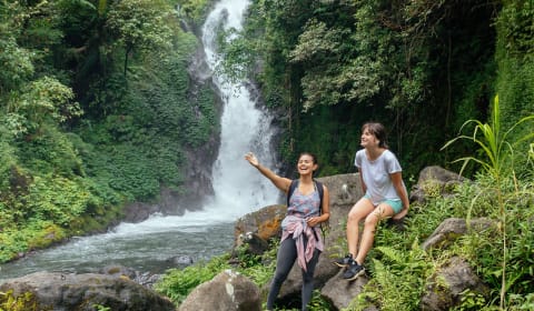 A Balinese local guide showing a tourist a waterfall