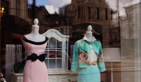 View through a window of a shop with 2 mannequins in dresses