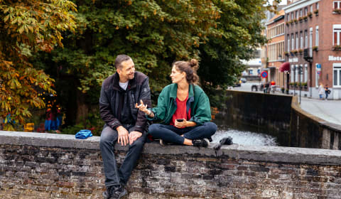 Two people having a conversation on a bridge in Bruges
