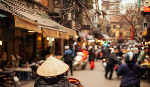 A busy street in Hanoi with a view of a local with a rice field hat