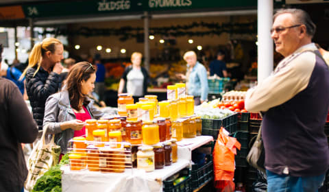 A market stall with a man selling glass pots of honey
