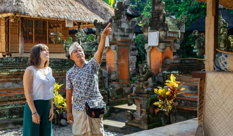 A Balinese local guide showing a tourist a temple on Bali