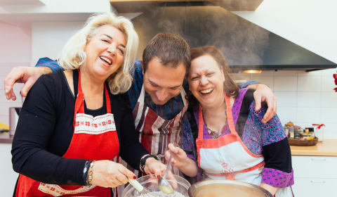 Two tourists and a local doing a cooking class in Athens and they are smiling