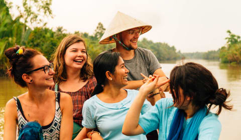 A group of tourists with a local guide on a boat in the Mekong Delta