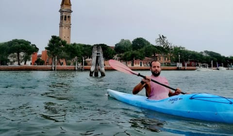 A tourist in a kayak on the lagoon in Venice