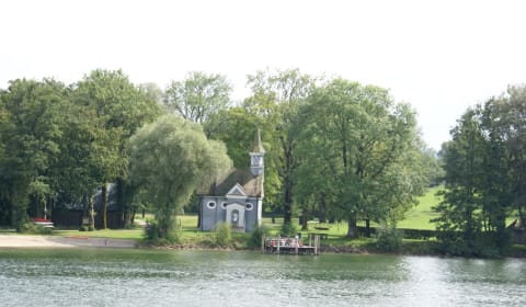 A small church in a park next to the water