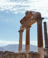 An ancient Roman pillars with Mount Vesuvius in the background